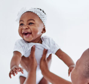 Un bebé sonriente sostenido por su madre